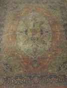 A machine made Persian design carpet, the central medallion in pale gold, cream, terracotta,