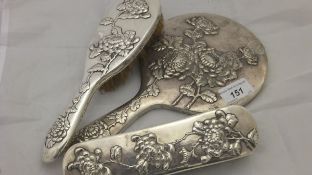 A Chinese silver backed three piece dressing table set by Wang Hing, comprising hand mirror,