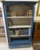 A modern painted open bookcase with three shelves over two drawers