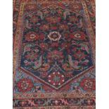 A Caucasian rug, the central dark blue ground with stylised floral motifs in terracotta, madder,