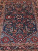 A Caucasian rug, the central dark blue ground with stylised floral motifs in terracotta, madder,