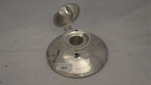 A silver capstan inkwell, the top inscribed "Rumble",