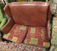 A red leather upholstered wing back two seat sofa in the 18th Century style,