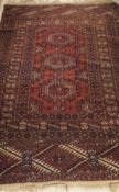 A Turkoman tribal rug, the three central medallions in terracotta, cream and blue/black,
