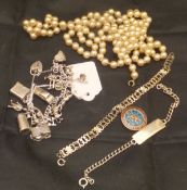 A white metal charm bracelet containing silver and white metal charms to include lock, piano,