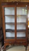 A mahogany two door display cabinet enclosing four shelves with two drawers below,