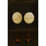 A pair of 19th Century mahogany pole screens in the Empire taste with oval painted silkwork maps of