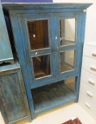 An Indian painted teak two glazed door display cabinet on square supports united by an undertier