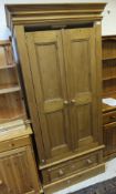 A modern pine wardrobe, the two cupboard doors above a single drawer,