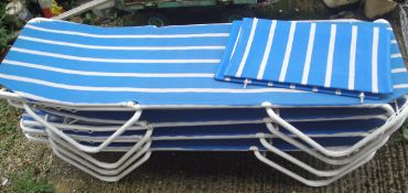 A set of four poolside loungers with blue and white striped seats