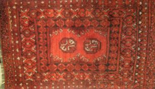 A small Bokhara rug, the two elephant foot medallions in burgundy, red,