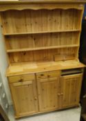 A modern pine dresser with two open shelves above three drawers and three cupboard doors,