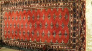 A Bokhara rug, the central red ground with repeating star shaped medallions in cream and black,