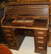 An early 20th Century oak tambour fronted desk with nine assorted drawers and fitted interior