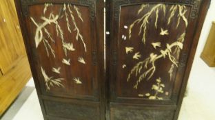 An Oriental hardwood two fold screen the arched top with carved decoration of birds and flowering