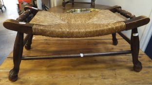 An early to mid 20th Century oak framed rush seated stool on splayed supports united by stretchers,