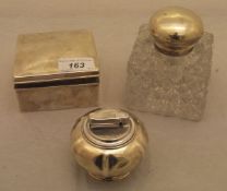 A silver topped glass bodied inkwell, a silver cigarette box and a silver cased table lighter,