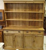 A large Victorian pine dresser of two shelves above two drawers and four cupboard doors on plinth