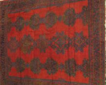 A Caucasian carpet, the central medallions in aubergine, blue and green on a red ground,