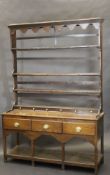 A late 18th or early 19th Century oak dresser with three plate racks above three drawers open under