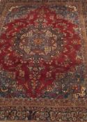 WITHDARWN A Persian rug, the red ground with central motif in blue, red, peach, pink, cream,