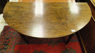 A mahogany gate leg oval topped dining table on turned legs to brass caps and castors