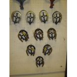 A collection of ten brass and wrought iron horse shoe shaped bridle hooks