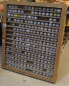 An oak wall display cabinet with multiple shelves containing golf balls