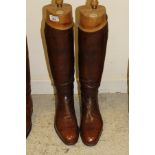 A pair of brown leather polo boots with wooden trees bearing ivory plaques inscribed "Tom Hill,