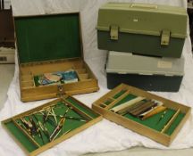 A cantilever tackle box containing a quantity of spinners, fixed spool reels,