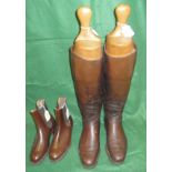 A pair of brown leather riding boots with wooden trees together with a pair of brown leather