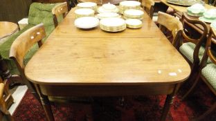 A Regency mahogany rounded rectangular dining table on slender turned and ringed tapered legs to