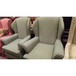 A pair of modern wingback armchairs with green and gold self pattern upholstery raised on plastic
