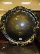 A Victorian black laquered papier mâché gilt decorated and floral spray painted circular tray