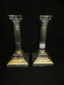 A pair of Edwardian silver Corinthian column candlesticks, raised on square bases (Sheffield,