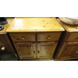 A pair of pine side cupboards, the plain tops above two drawers and two cupboard doors,