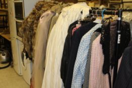 A rail containing various men's and ladies clothes to include jackets, dresses, etc,