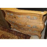 A Continental pine bombe fronted chest of three drawers with a shaped apron,
