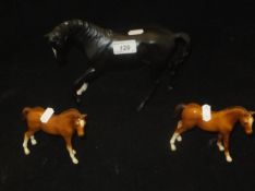 A Beswick figure of a black stallion with white sock and flash and two John Beswick chestnut foals