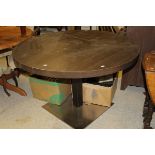 A modern circular dining table, the top of dark colouring,