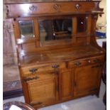 An early 20th Century oak dresser with mirrored back above a shaped serpentine fronted top,