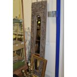 A narrow rectangular wall mirror with deep relief carved border decorated with leaves