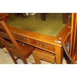 A modern yew wood writing table with green leather inset top above three drawers,