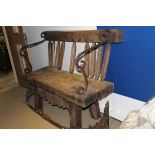 A rustic oak bench made from various parts with iron hand and arm rests