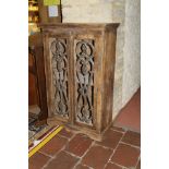 An Eastern hardwood cabinet with two doors set with ironwork panels enclosing two shelves