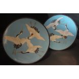 A pair of late 19th/early 20th Century cloisonné plates each decorated with three cranes on a sky