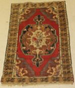 A Turkish rug, the central panel set with a floral decorated medallion on a red ground with blue,