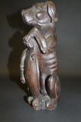An early carved oak figure of a dog sat upon it's haunches, bearing a shield between his front paws,