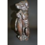 An early carved oak figure of a dog sat upon it's haunches, bearing a shield between his front paws,