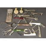 A collection of various corkscrews, wire cutters, can openers, sugar tongs,